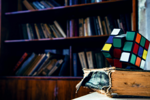 Unsolved Rubik’s cube on an old book in a library